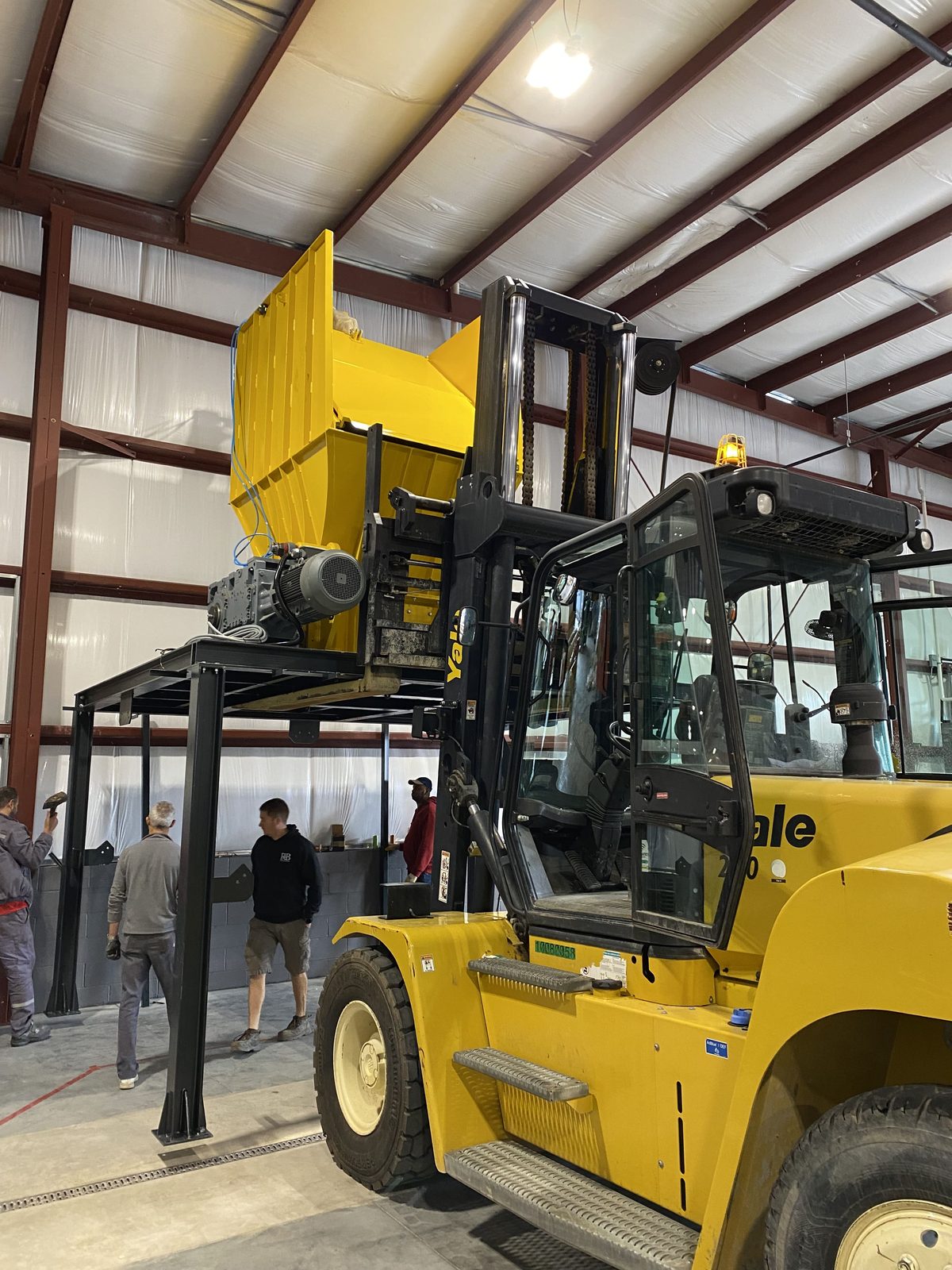 Forklift moving large mechanical equipment inside a plant